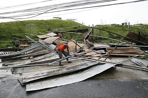 A Filipino government worker picks up pieces from a structure destroyed by strong winds from Typhoon Mangkhut as it barreled across Tuguegarao city in Cagayan province, northeastern Philippines . (Photo | AP)