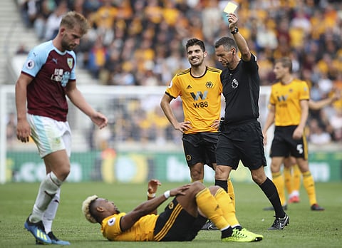 Burnley's Charlie Taylor (L) is shown a yellow card by referee Andre Marriner for a foul on Wolverhampton Wanderers' Adama Traore | AP