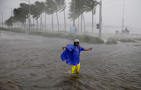 A man directs traffic to avoid a flooded street at the onslaught of Typhoon which barreled into the northeastern Philippines (File | AP)
