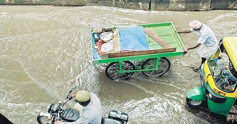 Commuters wade through rainwater logged on the road after a downpour in Pottery Town, on Monday| Pandarinath B
