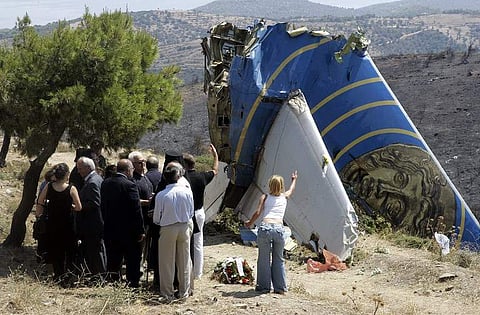 Relatives of victims and local people throw flowers, 16 August 2005 at the tail of the Cypriot plane that crashed 13 August on Grammmatiko hills in Varnava near Athens, during a church service for the victims. All 115 passengers and 6 crew members of the 