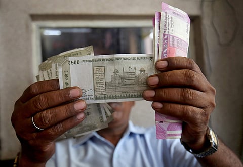 A cashier checks rupee notes inside a room at a fuel station in Ahmedabad, India. (Photo | Reuters)