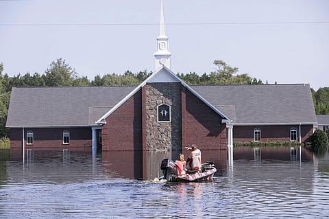 Marvin Singleton and Michele Larrimore motor past the Pine Grove Baptist Church on the way to check out Larrimore's home on Saturday, Sept. 22, 2018, in Brittons Neck, S.C. The flooding from the Little Pee Dee River is cresting on Saturday, but many resid