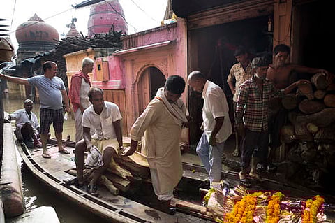 A dead body is transported on a boat through the flooded streets of Varanasi, near the Manikarnika Ghat. | AP