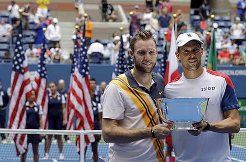 Jack Sock (L) and Mike Bryan hold the trophy after defeating Lukasz Kubot and Marcelo Melo in the men's doubles final of the US Open 2018 | AP