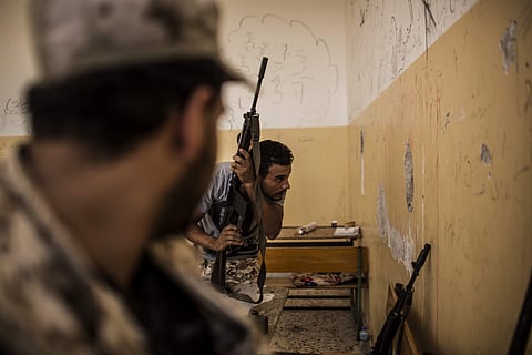 Fighter of the Libyan forces affiliated to the Tripoli government, looks through a spy hole chiseled through a wall towards Islamic State militant positions. | AP