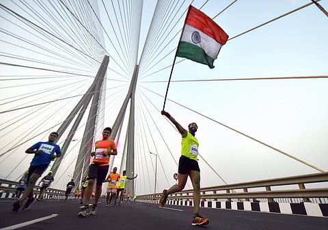 A participant runs with a Tricolour at Bandra-Worli Sea Link during Mumbai Marathon 2019. (Photo | PTI)