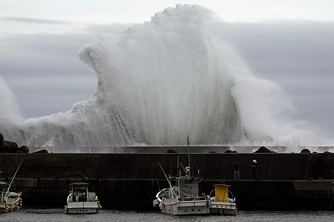 Men look at fishing boats as surging waves hit against the breakwater while Typhoon Hagibis approaches at a port in town of Kiho, Mie Prefecture, Japan. (Photo | AP)