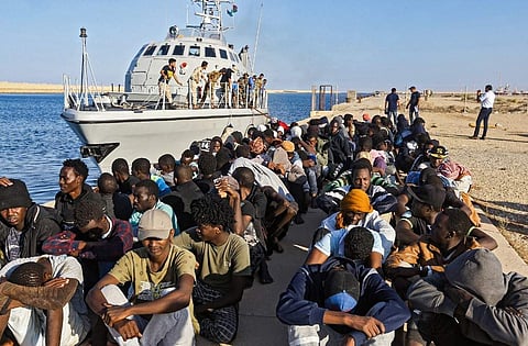 Rescued migrants sitting on a pier next to a Libyan coast guard ship in the town of Khoms (File photo| AFP)