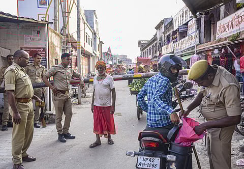 Police personnel checks a rider as other stand guard in Ayodhya. (Photo | PTI)