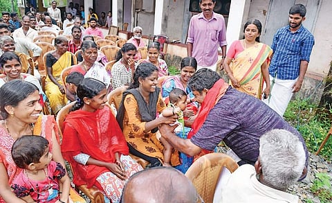 LDF candidate M Shankar Rai charming a child during electioneering at Mundyaduka in Puthige panchayat | Express
