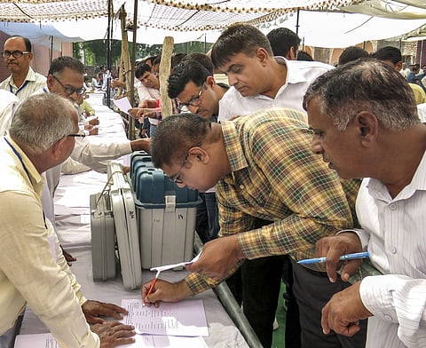 Polls officials collect EVMs and other election materials at a distribution centre on the eve of Haryana Assembly polls in Hisar. (Photo | PTI)