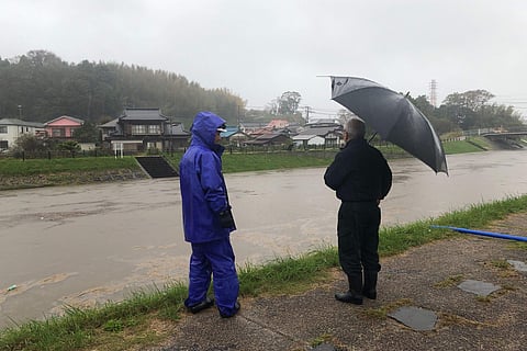 Men look at a swollen river due to heavy rain Friday, Oct. 25, 2019, in Narita, east of Tokyo. Torrential rain dumped from a low-pressure system hovering above Japan's main island triggered flooding in towns east of Tokyo, prompting fears of more damage t