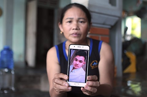 Hoang Thi Ai holds up her phone showing a photo of her son Hoang Van Tiep, who she fears is one of the possible victims in the truck deaths in England.