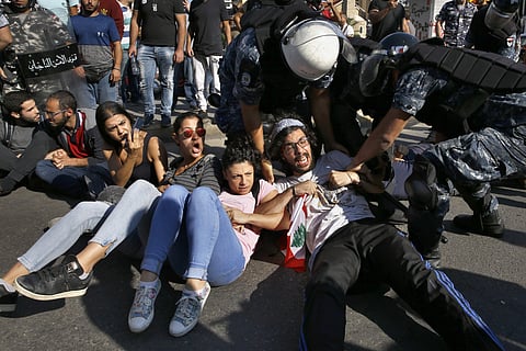 Anti-government protesters lie on a road, as they scream and hold each others while riot police try to remove them and open the road, in Beirut, Lebanon. (Photo | AP)