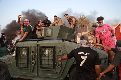 Anti-government protesters confront a soldier from the Federal Police Rapid Response Forces before they burn the armored vehicle, during a demonstration in Baghdad. (Photo | AP)