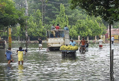 A fruit vendor pushes his cart through floodwaters in Patna. (Photo | PTI)