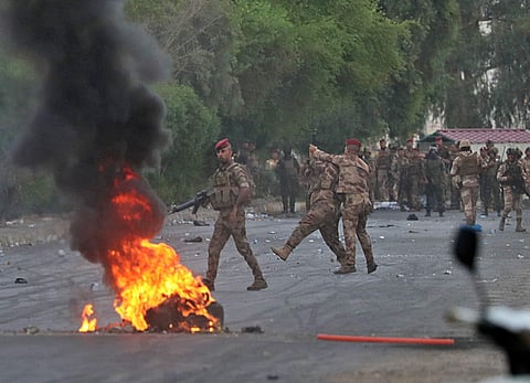 An Iraqi officer, center right, directs the soldier's weapon to the weapon that was shooting to disperse anti-government protesters during a demonstration in Baghdad. (Photo| AP)