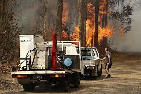 A local resident gets into his vehicle near a bushfire burning near Busbys Flat, Australia, Wednesday, Oct. 9, 2019.