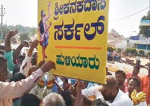 The media crew and enthusiasts cheer as the new board of the Kanakadasa Circle is installed at Huliyar in Tumakuru district on Thursday | Express