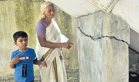 Harshamma Ramakrishnan and her grandson Gokul standing beside the pillar that developed a crack due to the demolition work at Maradu | A Sanesh