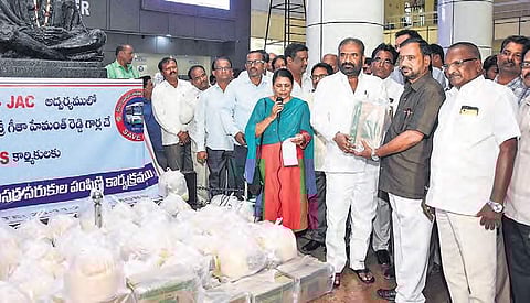 RTC JAC leader E Ashwathama Reddy distributing rice and other essential materials sponsored by NRI Geetha Mahendra Reddy to RTC employees at Mahatma Gandhi Bus Station on Saturday. (Photo | Vinay Madapu)