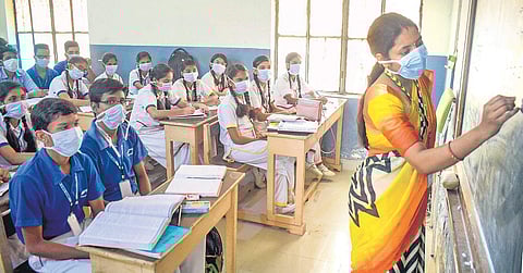 A teacher and her students wear pollution masks at a Gurugram school on. (Photo | PTI)