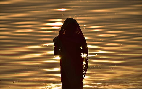 A Devotee prays to the sun god in Hussain Sagar lake during Chhat Puja. (Photo | EPS, Vinay Madapu P)
