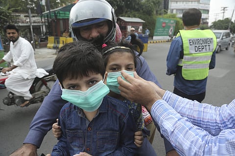 An environmental ministry official provides masks to children in Lahore (Photo| AP)
