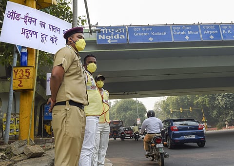 Civil Defence volunteers wearing masks stand near a placard asking people to obey the odd-even rule at ITO in New Delhi.| (Photo | PTI)