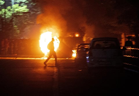 A protester throws a garbage can into a burning fire during a protest against the Citizenship Amendment Bill in Guwahati on Wednesday. (Photo | AP)