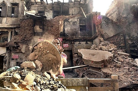 A woman works through the wreckage of a burnt house in Ahmedabad, 07 March 2002 (File Photo | AFP)