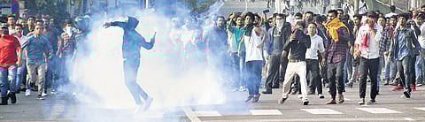 A protestor throws a teargas shell back towards the security forces during their protest march, near Janata Bhawan in Guwahati on Wednesday | PTI