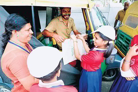 Students of Little Flower UP School in Kaloor, along with their teacher, selling  cloth bags made by them to autorickshaw drivers.