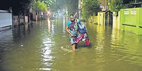 A woman struggles to walk through knee-deep water in the Chennai suburb of Korattur on Sunday evening. (Photo | Martin Louis, EPS)
