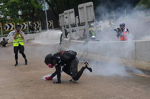 A protester tries to grab a teargas cannister fired by police during a demonstration. (Photo| AFP)