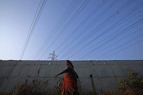 A woma walks under high-tension power lines leading from a Tata Power sub station in Mumbai's suburbs. Image used for representational purpose. (File Photo | Reuters)