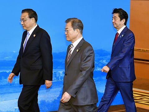 Chinese Premier Li Keqiang, left, South Korean President Moon Jae-in, center, and Japan's Prime Minister Shinzo Abe, right, walk to a group photo session before the trilateral meeting between China, South Korea and Japan in Chengdu, southwest China's Sich