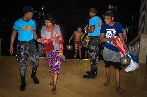 Police assist residents arriving at an evacuation centre, as typhoon Phanfone makes landfall, in Borongan, Eastern Samar province, central Philippines on December 24, 2019. (Photo | AFP)