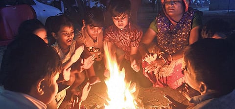 People warm themselves near a bonfire in Bhubaneswar on Sunday. (Photo | Biswanth Swain, EPS)