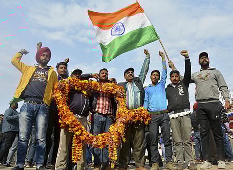Indians shout slogans carrying a huge garland as they wait to welcome Indian pilot at India Pakistan border at Wagah. (Photo | AP)