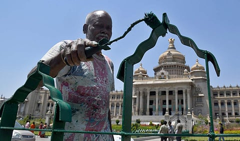A man paints a median barricade in front of Vidhana Soudha, in sweltering heat, in Bengaluru. (Photo| Pushkar V, EPS)