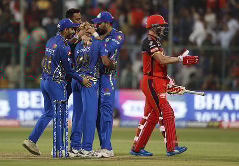 Mumbai Indians' players celebrate after their win as RCB's AB de Villiers walks past (Photo | AP)