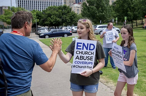 In this June 12, 2018, file photo, Claire Summers, 16, gets a high five as she and her sister Ella Summers, 10, right, protest the Southern Baptist Convention's treatment of women outside the convention's annual meeting at the Kay Bailey Hutchison Convent