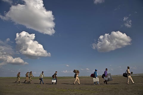 In this April 10, 2019 photo, election officials and paramilitary soldiers with election materials walk along the river Brahmaputra to board on a country boat on the eve of the first phase of general election in Majuli, Assam. (File Photo | AP)