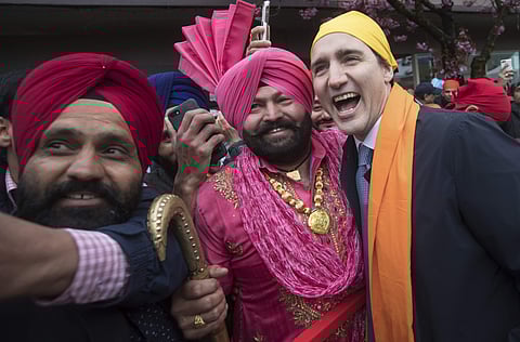 Prime Minister Justin Trudeau, right, poses for a photograph with Gurmukh Singh, center, after marching in the Vaisakhi parade, in Vancouver, British Columbia, Canada. (Photo | AP)