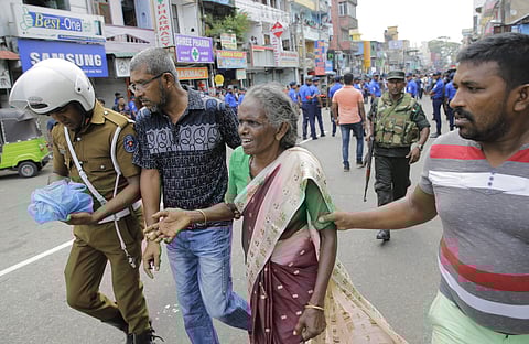 An elderly woman is helped near St. Anthony's Shrine after a blast in Colombo, Sri Lanka. (Photo | AP)