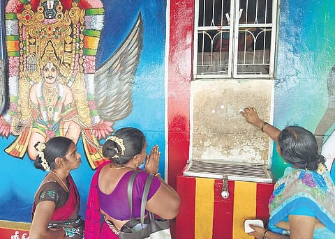 Devotees pressing coins against the sticky  ‘magic‘ wall at the  Karuppasamy temple | Express