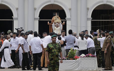 A Sri Lankan Catholic priest raises the statue of St. Anthony during a brief holly mass held outside the exploded church marking the seventh day of the Easter Sunday attacks in Colombo (Photo |AP)