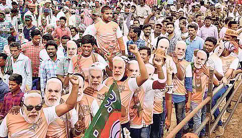 BJP supporters wearing Modi masks during a public meeting. | Express